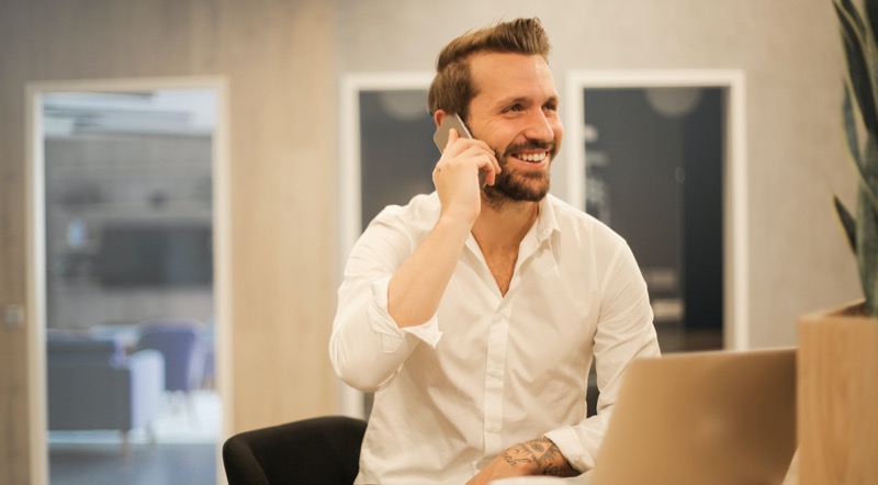 A man smiling on the phone in an office